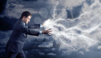 Young man with power doing lightnings from his hands over clouds