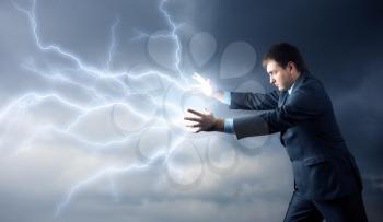 Young man with lightnings from his hands over clouds