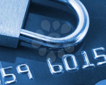 Close-up view of credit card and padlock. Toned in blue