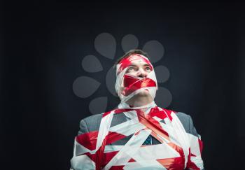Victum man with stripped  red and white duct tape over body