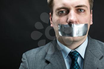 Man with mouth covered by masking tape preventing speech, studio shoot