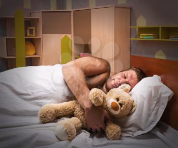 Sleeping man in bed hugs toy bear