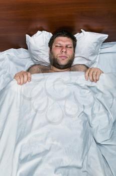 Top view of man sleeping in white bed