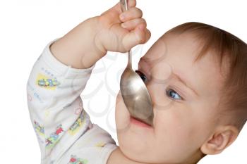 Baby girl holding spoon in mouth. Isolated on white