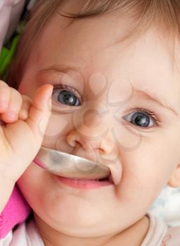 Portrait of happy baby girl holding spoon in mouth