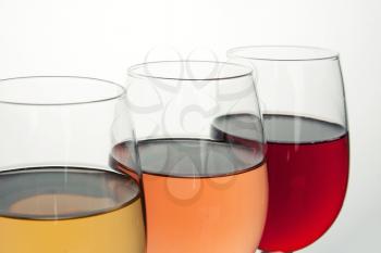 Close up of three glasses with red, rose and white wine isolated on white 