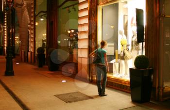 Woman near clothing store window at night