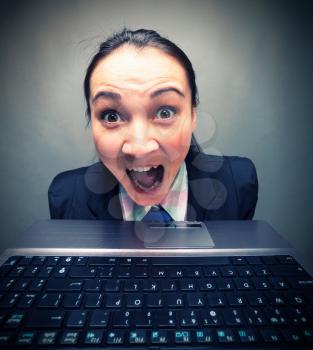 Young caucasian businesswoman screaming behind laptop
