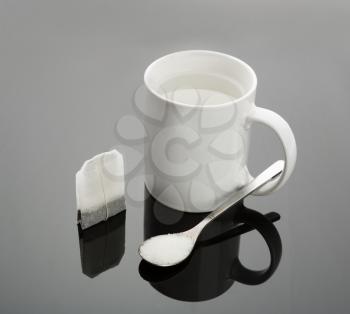 White cup with hot water, spoon and tea bag