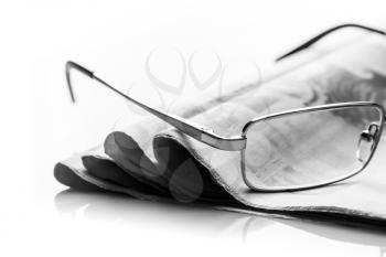 A closeup of glasses lieing on the heap of newspaper