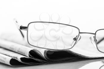 Closeup of glasses lieing on the heap of newspaper