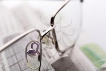 A closeup of glasses lieing on the newspaper
