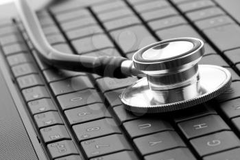 Medical stethoscope on laptop keyboard. In B/W