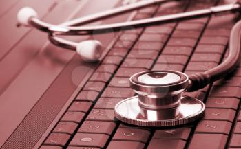 Medical stethoscope on laptop keyboard. Toned in red