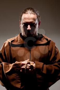 Portrait of medieval monk with cross rosary in shadow