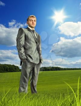 Confident businessman standing on meadow in beautiful day