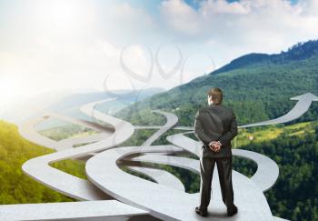 Businessman stands choosing his way on nature background