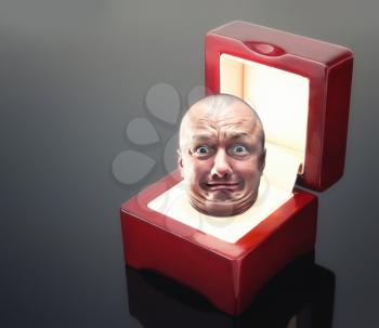 Male astonishad face in red jewelry box over grey