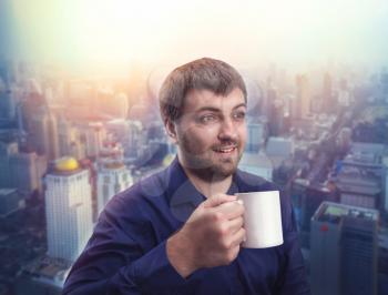 Adult man drinking coffee against evening city