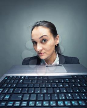 Young caucasian businesswoman hiding behind laptop