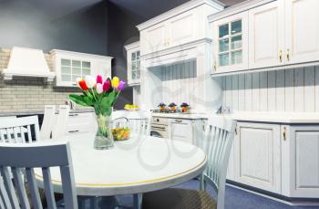 Luxury kitchen made from light wood with kitchen tools and tulip flowers