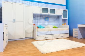 Bright child's bedroom with a bed with colorful pillows and cupboard
