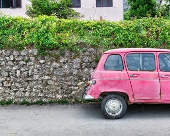 Old pink car near an old brick wall