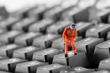Figurine of worker looking into pit in computer keyboard