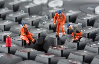 Small figurines of workers repairing computer keyboard