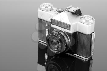 Old photographic camera on gray reflective surface