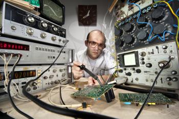 Funny nerd scientist soldering at vintage technological laboratory