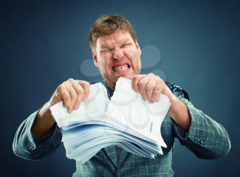 Angry man tearing out stack of paper