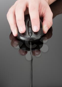 Hand holding computer mouse on reflective grey surface