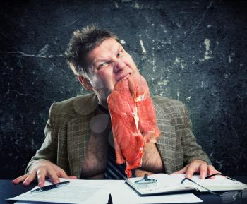 Crazy businessman with raw meat in his mouth