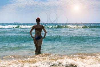 Woman standing back with hands on hips in the sea