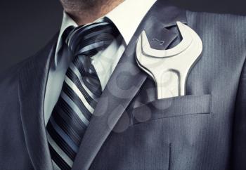 Businessman with spanner in suit pocket