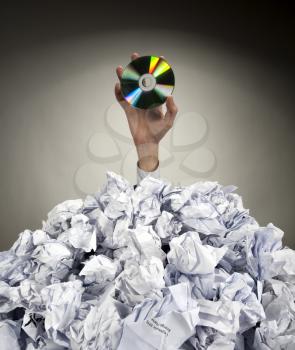 Hand with CD reaches out from big heap of crumpled papers