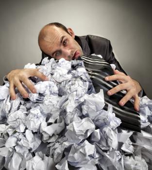 Exhausted depressive businessman laying on big heap of crumpled papers