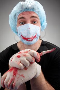 Mental sick blood soiled surgeon with knife