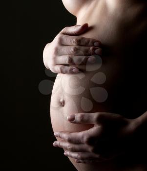Naked pregnant woman holding abdomen. Waiting for a child