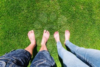 Two pairs of bare feet standing on the grass