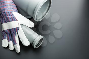 Soil-pipe and building glove on grey background