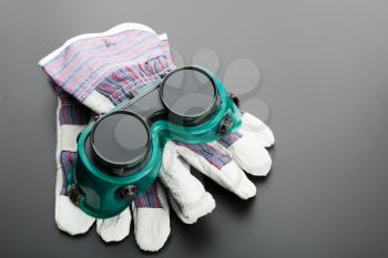 Gloves and protective glasses on grey background