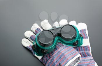Work gloves and protective glasses on grey background
