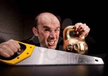 Crazy man with saw and heavy weight of gold