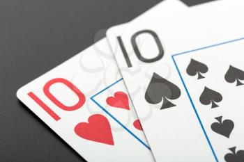 Two playing cards tens on grey background