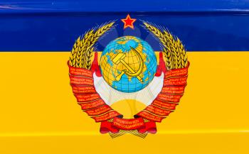 State emblem of the USSR over ukrainian flag