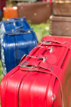 Red and blue old suitcases stand on the grass
