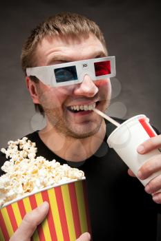 Funny man watching 3D movie, drinking soda and eating popcorn