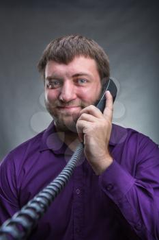 Smiling man speaks on the phone over grey